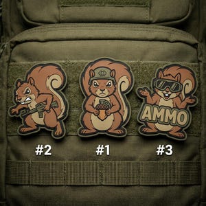 May include: Three embroidered patches featuring cartoon squirrels in various poses. One squirrel holds a weapon, another an acorn, and the third wears goggles with the word "AMMO". Each patch has a number: #2, #1, and #3.