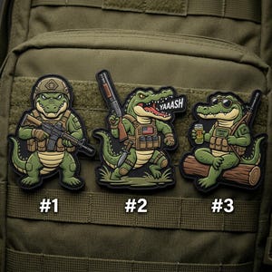 May include: Three cartoon alligator patches with military themes. One wears a helmet and holds a rifle, another has an American flag and the word "YAAASH", and the third wears sunglasses and holds a beer.