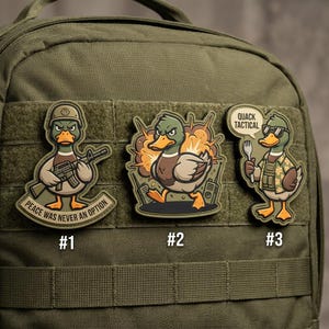 May include: Three embroidered patches featuring cartoon ducks with military themes. The first duck wears a helmet and holds a rifle, with the text "Peace Was Never An Option." The second duck is in an explosion. The third duck wears sunglasses and a tactical vest, with the text "Quack Tactical."