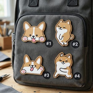 May include: A dark gray canvas backpack featuring four cartoon dog patches. Two patches show a Corgi with a tongue out, and two show a Shiba Inu in different poses. Each patch is labeled with a small black circular tag numbered #1, #2, #3, and #4.