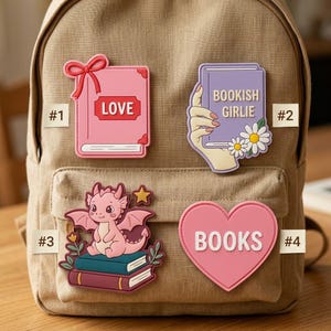 May include: Four decorative patches attached to a tan backpack. Patch #1 is a pink book with a red bow and the text LOVE. Patch #2 shows a hand holding a purple book with the text BOOKISH GIRLIE and daisies. Patch #3 features a pink dragon on books. Patch #4 is a pink heart with the text BOOKS.