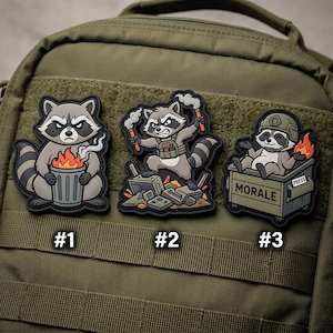 May include: Three embroidered patches featuring cartoon raccoons. One raccoon holds a trash can with flames, another stands on debris with flares, and the third sits in a box labeled "MORALE" with a helmet and flames. Each patch is numbered.