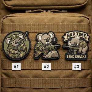 May include: Three tactical patches featuring cartoon koalas in military attire. One koala is sleeping with a rifle, another is aiming, and the third is sleeping with a rifle. The patches have the text "NAP TIME" and "SEND SNACKS".