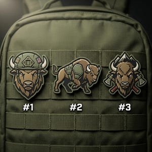 May include: Three embroidered patches featuring bison designs. One bison wears a helmet with an American flag, another has armor, and the third has crossed axes. The patches are brown, tan, and green, and are displayed on a green backpack.