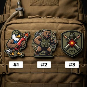 May include: Three embroidered patches with military-themed designs. One features an eagle holding a lit dynamite stick, another a bear in tactical gear, and the last a shield with crossed bullets and a grenade. Each patch has a number label.