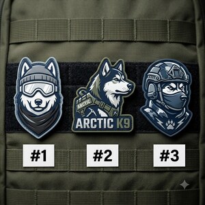 May include: Three tactical morale patches attached to an olive green MOLLE webbing panel. Patch #1 shows a husky wearing a beanie and goggles. Patch #2 features a husky profile with the text ARCTIC K9. Patch #3 depicts a husky in a tactical helmet.