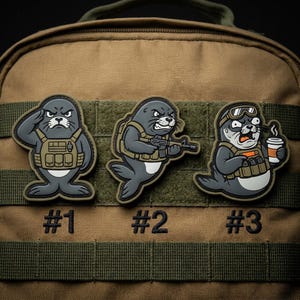 May include: Three cartoon patches featuring seals in tactical gear. One salutes, another holds a rifle, and the third holds a coffee cup. Each patch has a number: #1, #2, and #3, respectively. The patches are gray, tan, and black.
