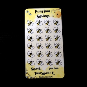 May include: A rectangular savings tracker card with a yellow and white background featuring the text Busy Bee Savings. The card displays a grid of twenty-eight bee illustrations, with text at the bottom reading Save £ per bee and Total Saved = £.