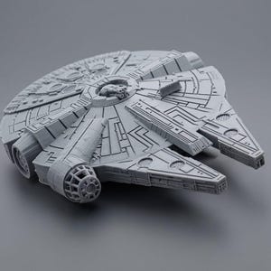 Może przedstawiać: Szczegółowy, szary model statku kosmicznego Millennium Falcon. Model posiada skomplikowane panele i elementy konstrukcyjne, w tym kultowe przednie szczęki i centralny obszar kokpitu. Okrągły korpus i prostokątne sekcje statku są dobrze widoczne.