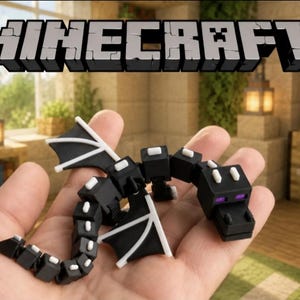 Pode incluir: Uma figura de brinquedo do dragão Ender do Minecraft em preto e branco com olhos roxos, apresentando um design articulado em blocos com detalhes de asas brancas e pequenos quadrados brancos ao longo do corpo segmentado, contra um fundo de jogo desfocado.