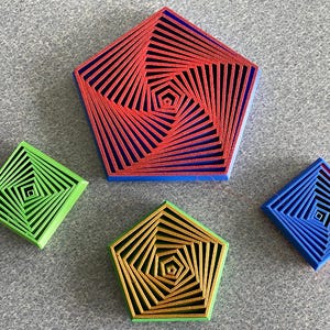 May include: A collection of four geometric objects featuring concentric, spiraling patterns. Two objects are pentagonal, one in red and blue and one in gold and green. Two objects are square, one in bright green and one in blue and red.