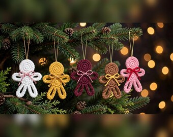 May include: Five crocheted gingerbread-style ornaments hanging from a pine tree. The figures are white, yellow, dark red, brown, and light pink. Each ornament features a small bow at the neck and a gold string loop for hanging on a branch.