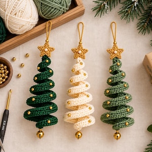 May include: Three spiral-shaped Christmas tree ornaments crocheted from yarn. Two are dark green and one is cream-colored. Each features a gold star at the top, small gold beads along the spiral, and a gold bell at the bottom with a hanging loop.