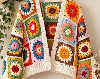May include: A long-sleeved cardigan made from multi-colored crochet granny squares featuring floral patterns in shades of red, yellow, orange, blue, green, and pink, finished with a cream-colored ribbed trim at the cuffs and front opening.