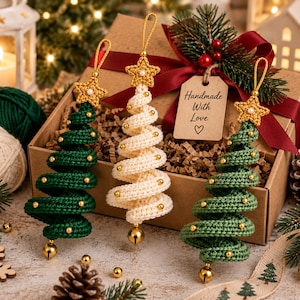 May include: Three spiral-shaped Christmas tree ornaments made of crocheted yarn. Two ornaments are dark green and one is cream-colored. Each tree is topped with a gold crocheted star and features small gold beads and a gold bell at the base.