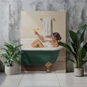 Könnte beinhalten: Ein Leinwanddruck zeigt eine Frau in einer mit Blasen gefüllten Badewanne, die einen Cocktail mit einer Orangenscheibe hochhält. Die dunkelgrüne Wanne hat goldfarbene Füße. Ein weißes Handtuch hängt an einem Holzhandtuchhalter.