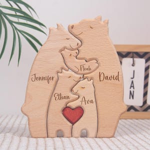 May include: Wooden family bear puzzle with the names Jennifer, Ethan, Ava, Noah, and David. The bears are light brown with a red heart. The puzzle is a decorative item.