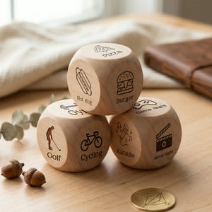 May include: Three wooden dice featuring engraved icons and text, including pizza, hot dog, burger, golf, cycling, karaoke, game night, and movie night. The dice are stacked on a wooden surface.