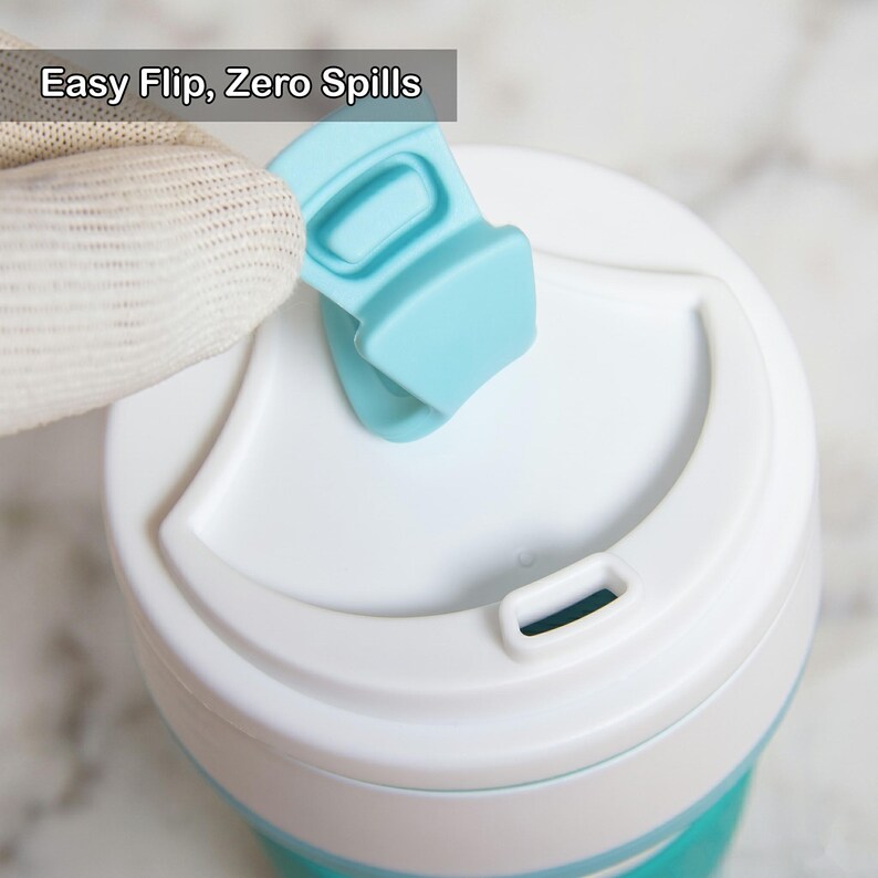 Detailed top-view shot demonstrating the easy-flip lid mechanism of a collapsible silicone cup. A gloved hand easily flips back the teal-colored cap from the spill-proof lid. This illustrates the simple and zero-spill design, ideal for hot coffee or other beverages.