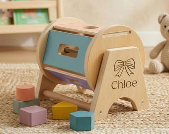 May include: Wooden toy with a rotating drum and colorful geometric shapes. The drum has a blue, pink, and purple interior. The name "Chloe" is engraved on the side. Includes a variety of colorful blocks.