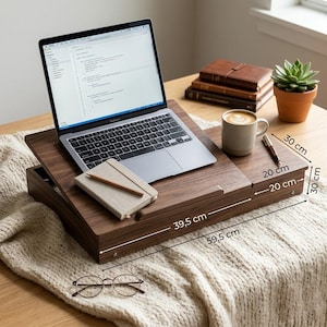 Op de afbeelding: Een houten laptoptafel met een laptop, notitieboek en pen. De tafel is 59,5 cm lang en 39,5 cm breed. Een koffiemok, een vetplant en boeken staan ook op de tafel.