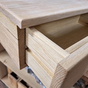 May include: A light-colored wooden drawer unit featuring a smooth, natural grain finish. The drawer is partially extended, revealing an open, empty interior compartment. The construction displays visible wood joinery and a clean, rectangular design.