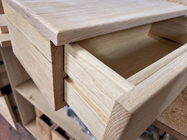May include: A light-colored wooden drawer unit featuring a smooth, natural grain finish. The drawer is partially extended, revealing an open, empty interior compartment. The construction displays visible wood joinery and a clean, rectangular design.