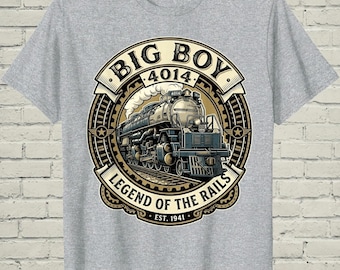May include: A heather gray t-shirt featuring a circular graphic of a steam locomotive. The text reads BIG BOY 4014 LEGEND OF THE RAILS EST. 1941. The design includes a train on tracks, smoke, and gear-like borders in shades of cream, black, and tan.