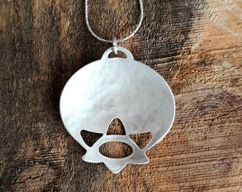 Puede incluir: Un collar con un colgante de plata con un diseño geométrico. El colgante tiene forma de flor con un centro redondo y cinco pétalos.