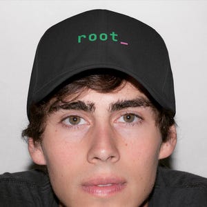 May include: A black baseball cap featuring the text root_ embroidered in green with a pink underscore. The cap has a structured crown and a curved brim, providing a classic look. The design is centered on the front panel of the hat.