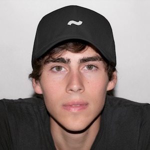 May include: Black baseball cap with a white wave logo. The cap is made of a smooth material and has a curved brim. The cap is worn by a person wearing a black shirt.