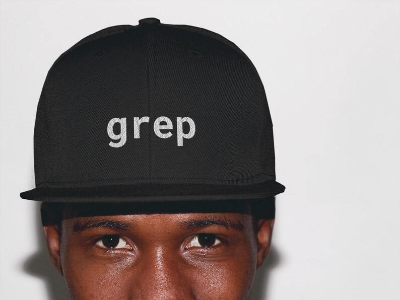 May include: Black baseball cap with the word "grep" embroidered in white. The cap features a flat peak and a structured design. A classic style hat, suitable for casual wear.