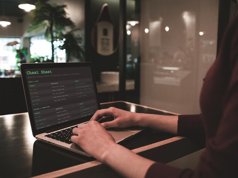 Pu&ograve; includere: Un laptop mostra una "Cheat Sheet" sullo schermo. Il testo verde risalta su uno sfondo scuro. Il laptop &egrave; appoggiato su una superficie di legno scuro. Le mani della persona sono sulla tastiera.