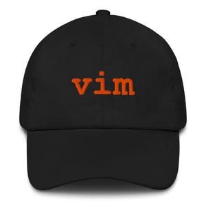May include: Black baseball cap with the orange embroidered word "vim" on the front. The cap has a curved brim and a fabric strap closure at the back. A classic, casual hat.