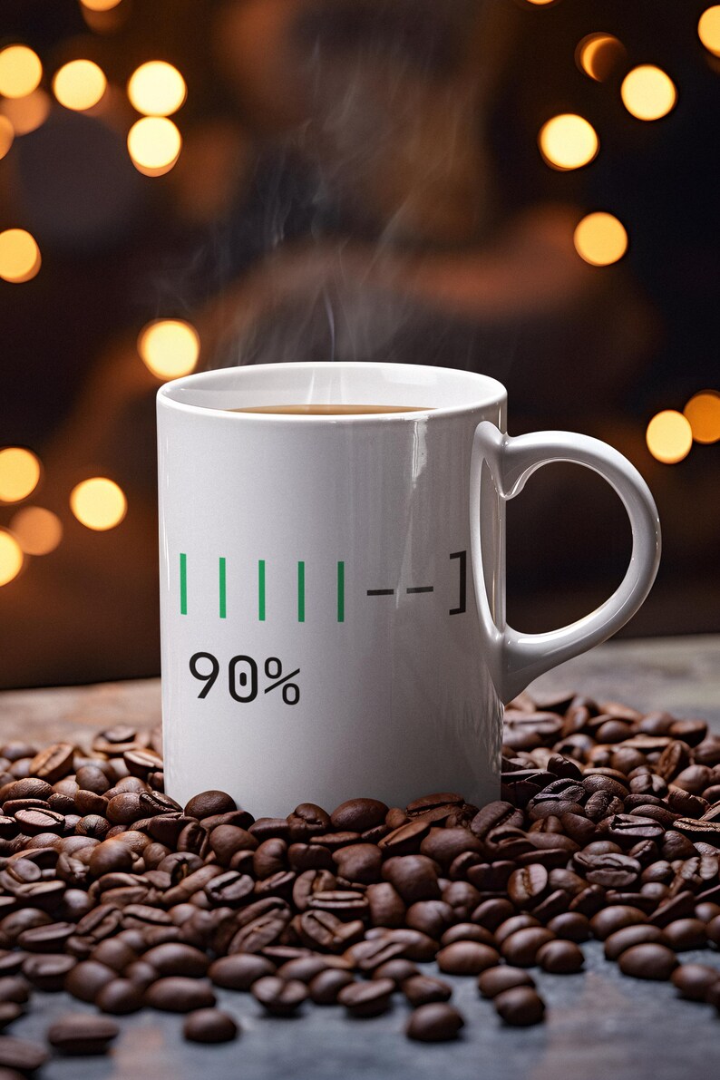 May include: A white coffee mug with a black handle, filled with coffee and steam rising from the top. The mug has a green and black graphic that reads "90%" on the side. The mug is surrounded by roasted coffee beans.