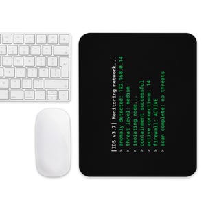 May include: Black rectangular mousepad with green text displaying network monitoring information. A white keyboard and mouse are in the image. The mousepad text includes "anomaly detected" and "firewall: ACTIVE".