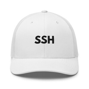 May include: White trucker hat with a curved brim and mesh back. The front of the hat features the embroidered letters "SSH" in black. A casual accessory for everyday wear.