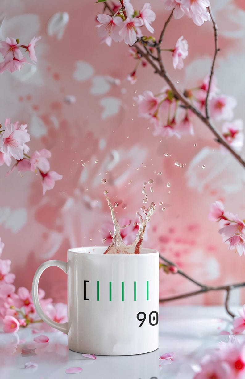 May include: A white ceramic mug with green vertical lines and the number 90, with liquid splashing out. The mug is set against a soft pink background with cherry blossom branches and flowers.