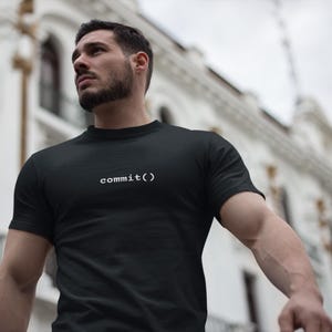 Peut inclure: Un t-shirt noir à manches courtes avec le texte blanc commit() imprimé dans une police à chasse fixe au centre de la poitrine. Le vêtement présente une encolure ronde classique et une conception en tissu noir uni sur tout le torse.