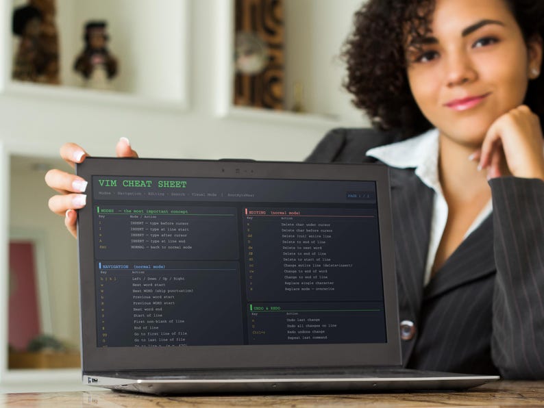 Pu&ograve; includere: Un laptop mostra una "VIM CHEAT SHEET" con comandi e istruzioni. Lo schermo &egrave; nero con testo bianco e verde. Una donna con una giacca nera e una camicia bianca tiene il laptop, sorridendo.