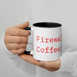 May include: White coffee mug with a black interior and handle. The mug features the red text "Firewall Coffee:" on the front. The mug is held by a person.