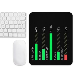 May include: A computer mouse and keyboard are next to a black mousepad. The mousepad has a graphic with green and red bars representing CPU load, memory, caffeine, focus, and bug count, with percentages displayed.