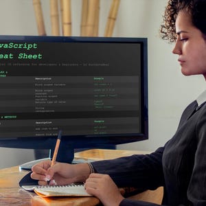 以下が含まれることがあります： コンピューターモニターには、開発者向けの重要なJSリファレンスである「JavaScript Cheat Sheet」が表示されています。 ブレザーを着た人がペンでノートに書いています。 背景には竹が含まれています。
