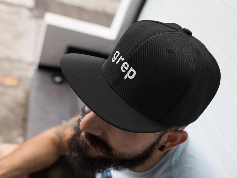 May include: Black baseball cap with a flat brim, featuring the word "grep" embroidered in white. The cap has a structured crown and a flat peak. A classic style, suitable for casual wear.