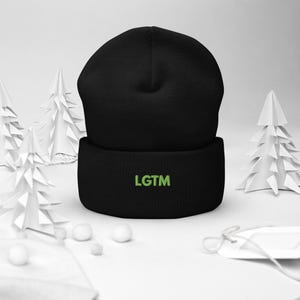 May include: A solid black cuffed beanie featuring the text LGTM embroidered in lime green thread on the front fold. The knit hat has a rounded crown and a thick, ribbed cuff that sits horizontally across the base of the garment.