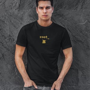 May include: A black short-sleeved t-shirt featuring the yellow text "root_" above a small yellow graphic of a tree stump. The shirt has a crew neckline and a standard fit, constructed from a solid black fabric with a clean, simple design.
