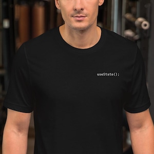 May include: Black t-shirt with the text "useState();" printed in white. The shirt is a solid black color and has a crew neck.