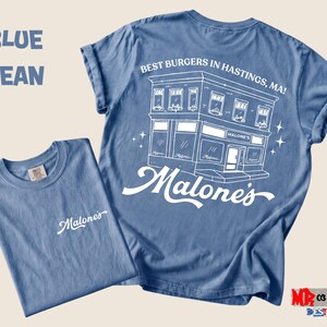 a blue t-shirt with a graphic design of a building and the text "Malone's" printed on it.