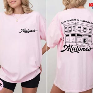 A woman wearing a pink t-shirt with a graphic design on the back.