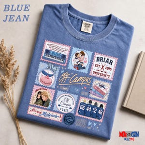 a blue t-shirt with various colorful and whimsical designs, including a couple embracing, a piano, and other decorative elements. The t-shirt is laid out on a surface, and there are some decorative elements like a book and a plant nearby.